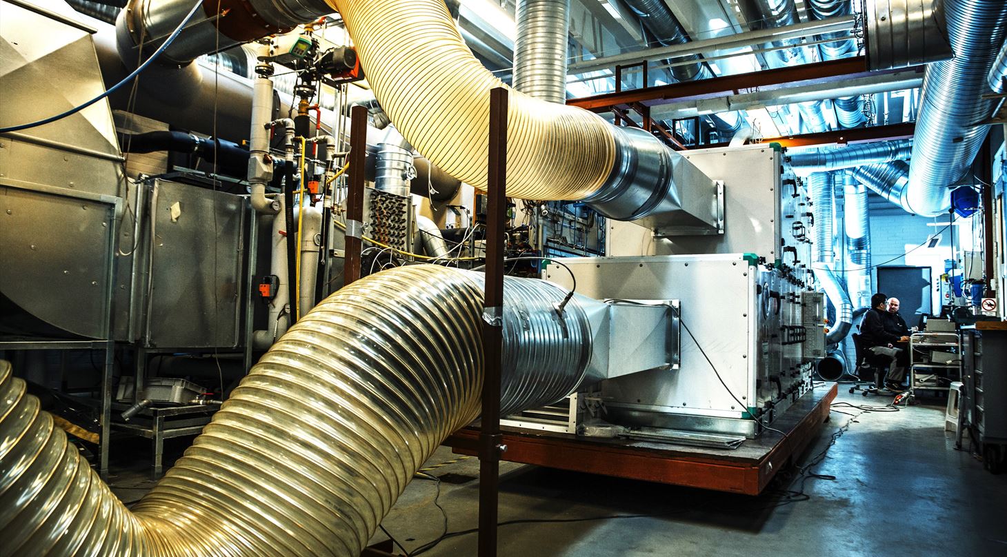 Ventilationsanlæg og testudstyr med store fleksible luftkanaler i Air Handling Unit-laboratoriet.